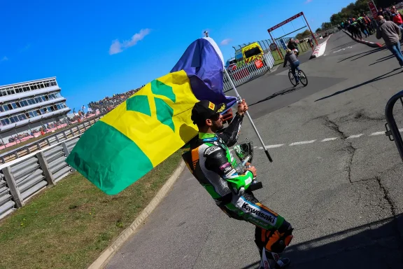 Asher with the flag of St Vincent at Brands Hatch celebrating another top finish on the Kawasaki